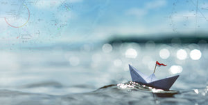 Das Titelbild zeigt ein gefaltetes Papierschiff. Das Schiff schwimmt auf einer funkelnden Wasserfläche. Am Horizont scheinen durch den blaugrauen Himmel verschiedene Elemente einer Seekarte.